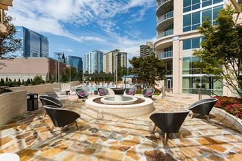 an outdoor patio with a firepit and lounge chairs with a city skyline in the background